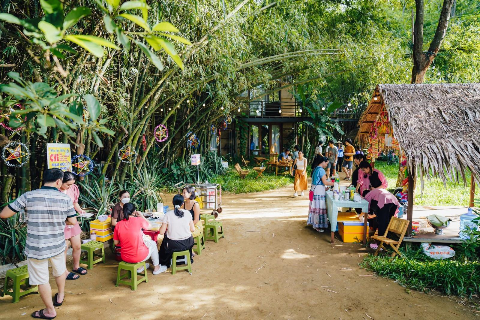 Villagers and visitors sharing food under bamboo at Triêm Tây Village